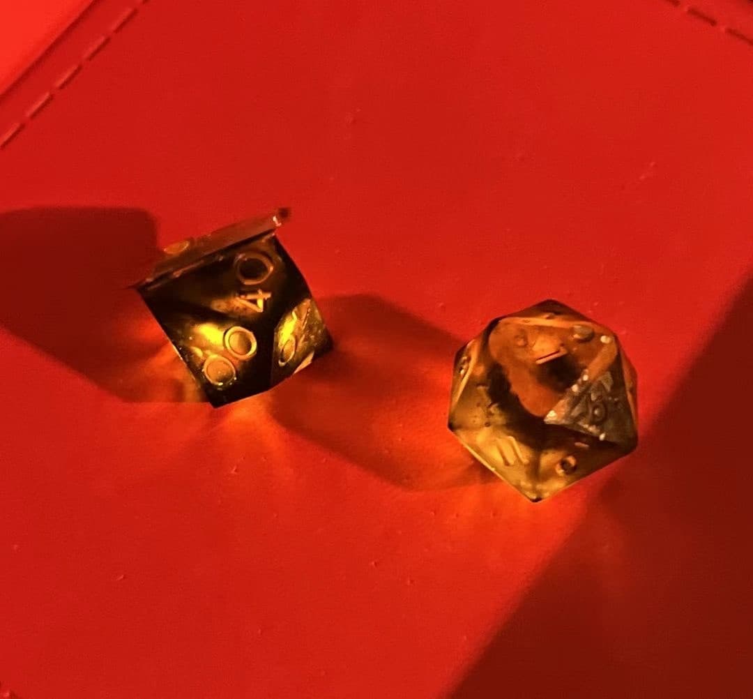 Two illuminated dice glowing amber in a red dice tray